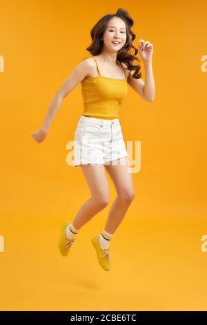 Foto girata a tutta lunghezza del corpo di eccitata estatica bella ragazza attraente isolato su sfondo giallo Foto Stock