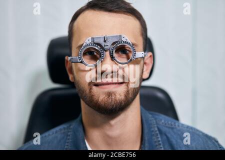 Health care, medicina, la gente, la vista e il concetto di tecnologia - allegro uomo è verificata visione a occhio clinica o un negozio di ottica Foto Stock