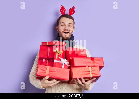 Barba elegante con viso piacevole, foulard grigio scuro, pullover caldo e confortevole, con set di preimpostazioni e regali in scatole rosse, apre allegramente il mou Foto Stock