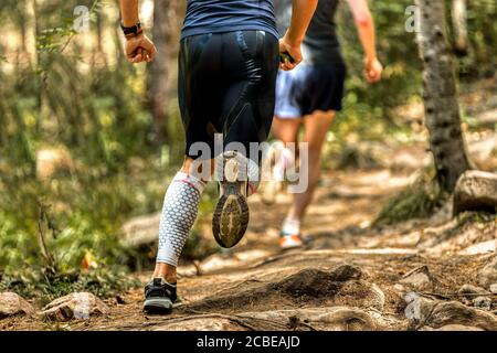 indietro uomo runner in calze a compressione running pietre sentiero Foto Stock
