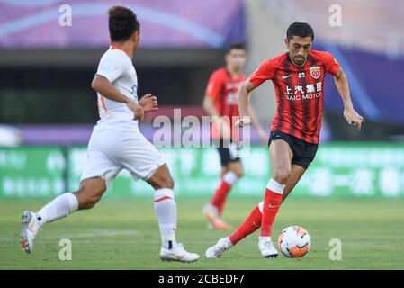 Il calciatore uzbeko Odil Ahmedov di Shanghai SIGG F.C., a destra, protegge la palla durante la quarta partita della Super League Cinese 2020 (CSL) contro Wuhan Zall F.C., Suzhou città, provincia di Jiangsu della Cina orientale, 12 agosto 2020. Shanghai SIPG F.C. sconfisse Wuhan Zall F.C. con 2-1. Foto Stock