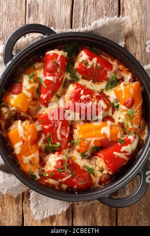 Peperoni ripieni al forno con riso, carne, formaggio e pomodori da vicino in una padella sul tavolo. Vista dall'alto verticale Foto Stock