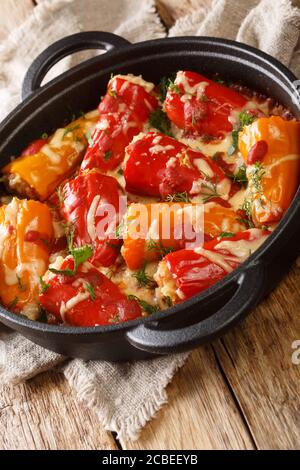 Peperoni ripieni al forno con riso, carne, formaggio e pomodori da vicino in una padella sul tavolo. Verticale Foto Stock