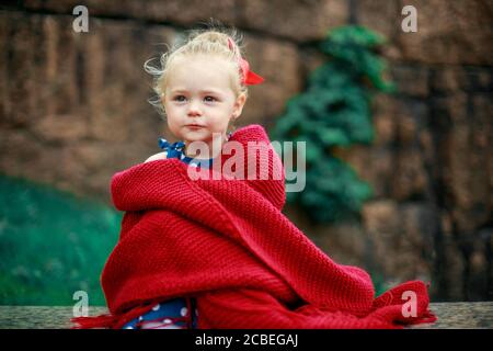 triste ragazza seduta avvolto in una plaid borgogna Foto Stock