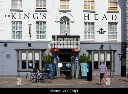 Uomo che cammina oltre il King's Head nel mercato del sabato, Beverley, East Yorkshire, Inghilterra Regno Unito Foto Stock