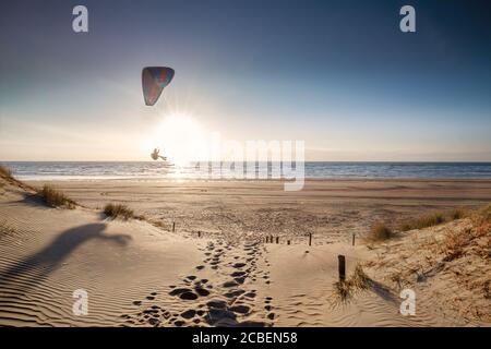 uomo parapendio sulla spiaggia al tramonto in estate Foto Stock