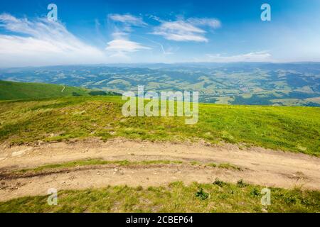 strada montana attraverso prati erbosi. meravigliosa avventura estiva. nuvole sul cielo blu Foto Stock