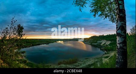 Le nuvole sono colorate in diverse sfumature al tramonto sul lago. Foto Stock