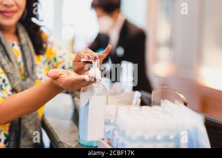 Donna che lava a mano gel di alcol alla reception dell'hotel per la fermata covid 19 sparsi. Foto Stock