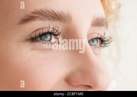 Laughing. Primo piano del volto della bella giovane donna caucasica, concentrarsi sugli occhi. Emozioni umane, espressione facciale, cosmetologia, concetto di cura del corpo e della pelle. Guance ben tenute, trucco narutale. Benessere. Foto Stock