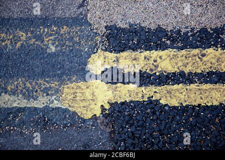 Un primo piano di segnaletica stradale con doppia linea gialla a lato del marciapiede Foto Stock