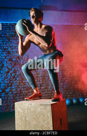 Man Doing Box Jump aggiunge una buona dose di virtuosità per una maggiore velocità, efficienza e grazia, come in qualsiasi movimento CrossFit. Foto Stock