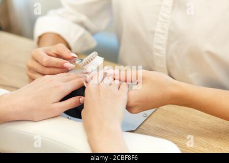 Le mani delle giovani donne che fanno i chiodi sul tavolo di legno. Cura di bellezza. Manicure closeup. Foto Stock