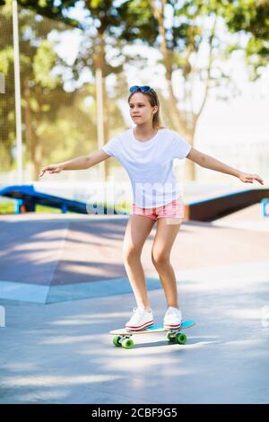 La ragazza teenager corre uno skateboard nel parco Foto Stock