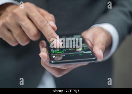 Primo piano di mani umane che controllano le tabelle di stock finanziario su. Foto Stock