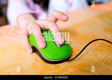 Mano su un mouse del computer. La mano del bambino guida l'apprendimento con la tecnologia. Foto Stock