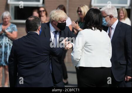 Il primo Ministro Boris Johnson viene presentato al personale dal Ministro della Sanità dell'Irlanda del Nord Robin Swann (a sinistra) quando arriva al quartier generale del Servizio di ambulanza dell'Irlanda del Nord durante la sua visita a Belfast. Foto Stock