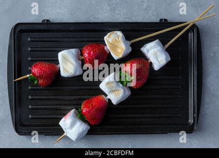 Gourmet Grilled Strawberry e Marshmallow on Stick su spiedini di legno su sfondo grigio. Foto Stock