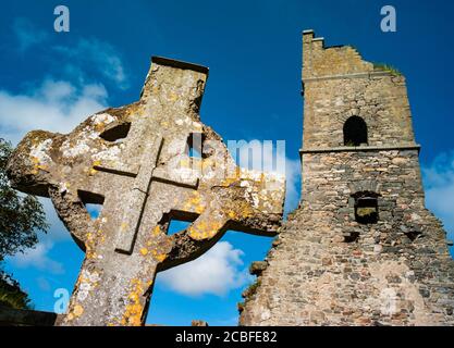 Antica lapide a croce celtica e rovine della chiesa in Irlanda rurale Foto Stock
