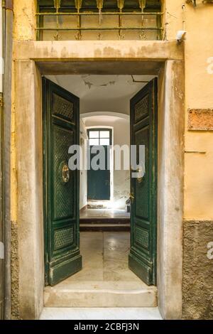 Il doppio ingresso di una tipica casa antica nel centro storico con porte in legno che si aprono sul corridoio con pavimento in marmo, Liguria, Italia Foto Stock