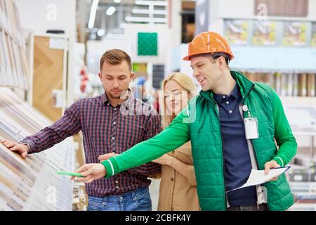 bella coppia clienti ha chiesto aiuto e consigli da warehouse worker nel mercato, lavoratore in uniforme è credibile Foto Stock