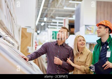 utile lavoratore di magazzino affabile aiutare i clienti con la scelta, uomo uso documento in cui tutte le istruzioni e i vantaggi di merce sono strangati Foto Stock