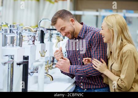 coppia positiva risata nel mercato, tenere maniglia per doccia e parlare con l'uso di esso, coppia sposata hanno divertimento, fare l'acquisto, vogliono acquistare doccia Foto Stock