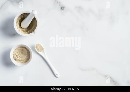 Preparazione maschera facciale cosmetica Ubtan. Polvere di Ubtan in ciotola e Malta su tavola di marmo. Confezioni ayurvediche per viso e corpo Foto Stock