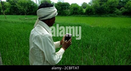 DISTRETTO KATNI, INDIA - 20 AGOSTO 2019: Un villaggio indiano povero contadino tradizionale funzionamento smart phone concetto per la gente asiatica apprendimento digitale a. Foto Stock