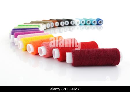 bobine di cotone colorate in un arco su bianco con poco profondo profondità di campo Foto Stock