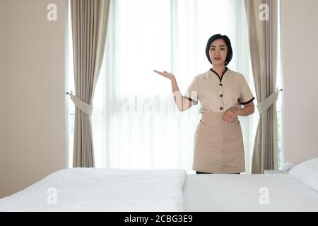 La giovane cameriera asiatica nella camera d'albergo a cui lei si allontina fotocamera Foto Stock