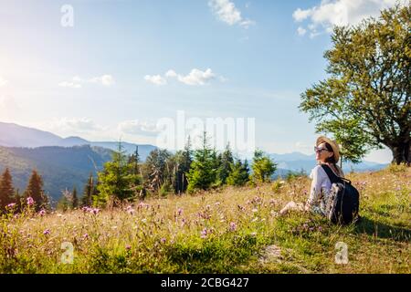 Viaggiare in Ucraina estate. Gita ai Monti Carpazi. Felice donna turista trekking seduta in fiori Foto Stock