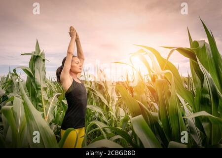 Donna sportiva che pratica yoga e meditating all'alba all'aperto in natura Foto Stock