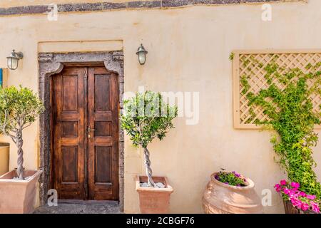 Vecchie strade affascinanti, Francia meridionale, Provenza. Antica porta in legno con fiori di bouganville e piante verdi in vasi di ceramica Foto Stock