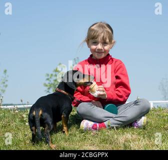 Bambina che mangia icecream con il suo cane Foto Stock