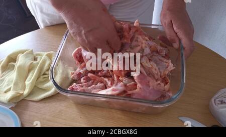 Chef che mescola zampe di pollo crudo per barbecue con ciotola con marinata. Spezie e salsa sono mescolate con cosce di pollo. Primo piano Foto Stock