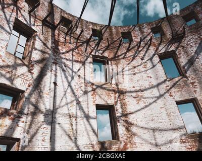 Muro di mattoni ricurvi di edificio rovinato. Cielo è visibile attraverso le finestre. Parte di casa distrutta. Architettura vecchia Foto Stock