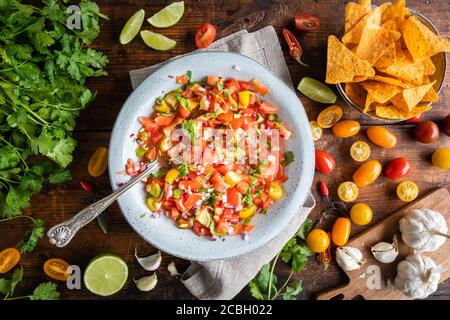 Tex Mex Pico de Gallo con nacho tortilla chips. La ciotola di salsa di pomodoro è vista dall'alto, piatto, e ci sono ingredienti tipici come la ciccia Foto Stock