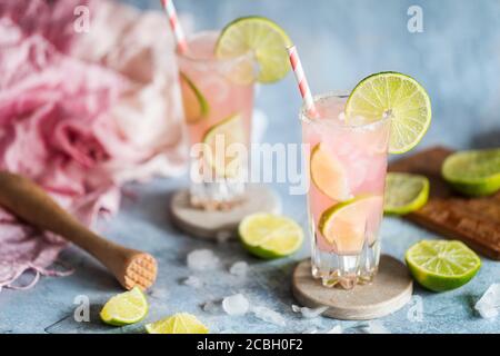 Un cocktail fresco con succo di lime e pompelmo rosa. Cocktail Paloma. Due bicchieri sul tavolo e hanno carta ecologica str Foto Stock