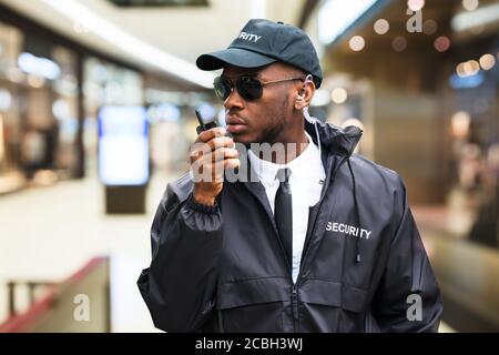 Guardia di sicurezza che usa Walkie Talkie nel centro commerciale Foto Stock