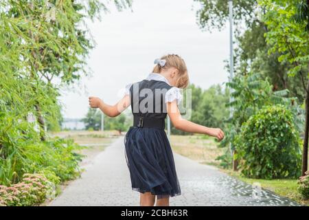 Una bambina giovane si prepara a camminare a scuola. Adolescente in autunno nel cortile Foto Stock