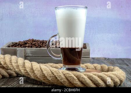 Caffe mocha con panna montata. Latte macchiato in un bicchiere alto. Un bicchiere di latte di caffè e chicchi di caffè su sfondo scuro. Сopy spazio Foto Stock