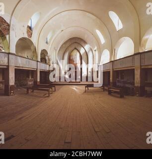 All'interno di un'antica chiesa abbandonata, antico interno di edificio religioso, panchine e altare, all'angolo si trova una croce di legno Foto Stock