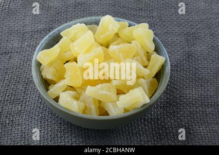 Secchi pezzi di ananas disidratati in ceramica ciotola di spuntini su tovaglia di burlap Foto Stock