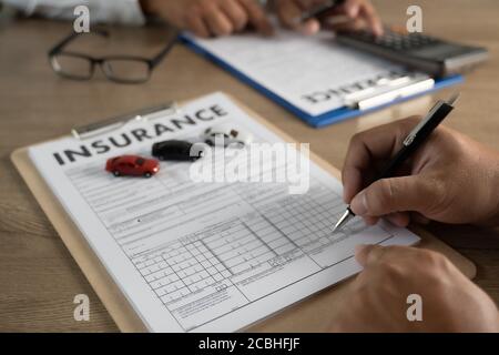 polizza assicurativa e puntando esaminare la polizza assicurativa dell'automobile dettaglio al cliente Foto Stock