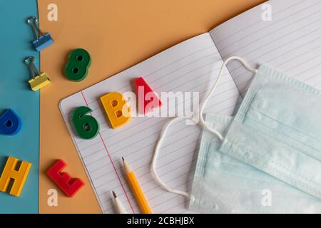 Disposizione di varie forniture scolastiche. Cancelleria scolastica, maschere mediche. Riapertura scolastica, ritorno a scuola dopo la pandemia covid-19, nuova Foto Stock