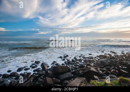 Onde oceaniche che si infrangono sulla spiaggia rocciosa Foto Stock