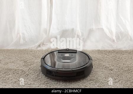 La mano accende l'aspirapolvere robot rotondo Foto Stock