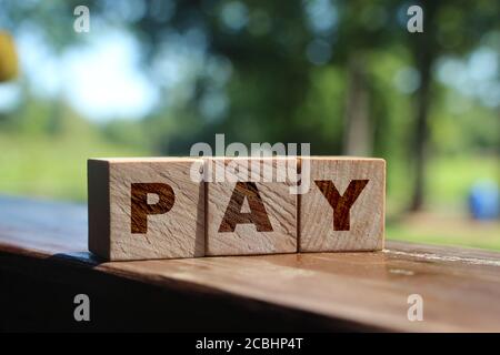 Paga su cubetti di legno con sfondo naturale. Concetto finanziario di tasse e tasse Foto Stock