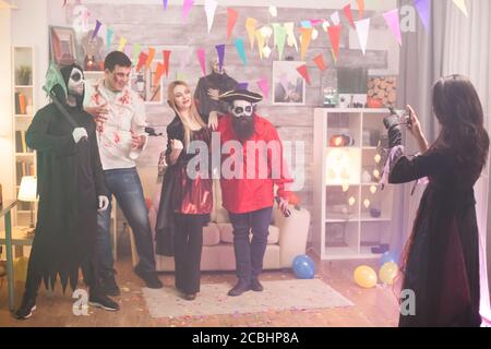 Vista posteriore della strega scattando foto del pirata e dei suoi amici durante la festa di Halloween. Foto Stock